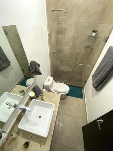 een badkamer met een wastafel, een toilet en een douche bij Casa familiar cerca de la playa con terraza privada in Cancun