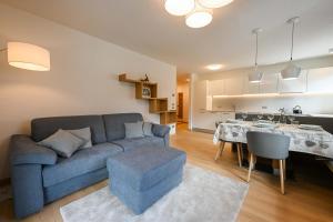 ein Wohnzimmer mit einem blauen Sofa und einem Tisch in der Unterkunft Casa al Parco Deluxe in Canazei