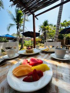 a wooden table with plates of fruit on it at Rosario EcoHotel in Isla Grande
