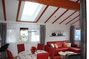 a living room with a red couch and a table at Chalet Gerbera in Wengen