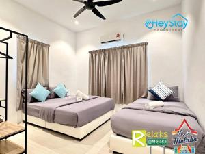 a bedroom with two beds and a ceiling fan at Klebang Villa 17Pax PrivateSwimmingPool TownArea By Heystay Management in Melaka