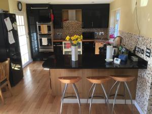 a kitchen with a black counter and two stools at 9 Chudleigh Close in Bedford