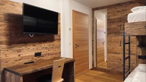 um quarto com uma televisão numa parede de madeira em Appartments Raffele em San Candido