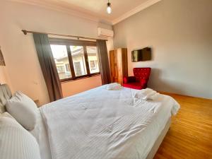 a bedroom with a white bed and a red chair at Ali Apart in Antalya