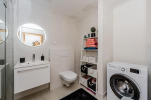 a bathroom with a toilet and a sink and a washing machine at Mesiheina Apartment in Pärnu