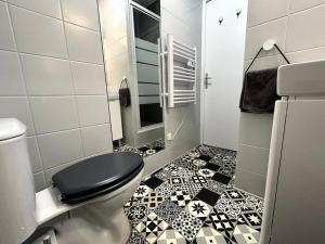 a bathroom with a toilet and a black and white tile floor at Logement Neuf - Proximité Centre in Bourges