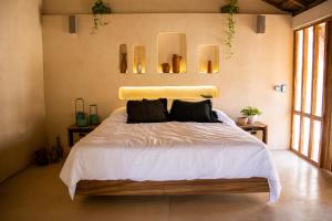 1 dormitorio con 1 cama con sábanas blancas y almohadas negras en BH Hotel & Cenote Tulum - Adults Only en Tulum