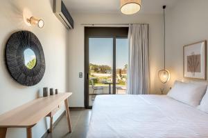 Schlafzimmer mit einem Bett, einem Tisch und einem Spiegel in der Unterkunft Plakias Suites COCO-MAT Full Experience in Plakias