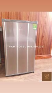 einen Metallkühlschrank in einem Zimmer mit einer Holzwand in der Unterkunft Khach san Nam Hotel in Bản Co