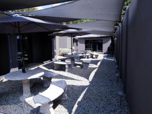 - une rangée de tables de pique-nique et de parasols sur une terrasse dans l'établissement Haleys Guest House, à Benoni