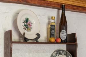a shelf with a bottle of wine and a plate and two apples at Casa Lavoura em Requeixo in Celorico de Basto