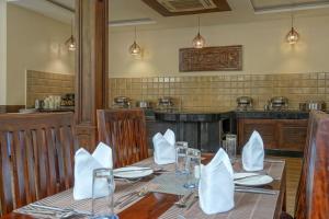 帕哈尔加姆The Chinar Resort & Spa, Pahalgam的用餐室配有带白色餐巾的桌子