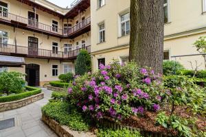 a building with purple flowers in front of a tree at Elegant Apartments in Krakow