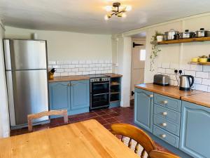 uma cozinha com armários azuis, uma mesa e um frigorífico em Elbury Lodge em Exeter