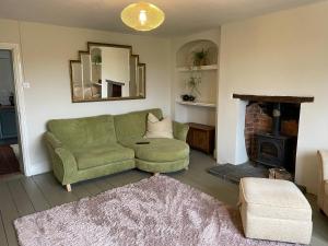 a living room with a green couch and a fireplace at Elbury Lodge in Exeter