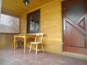 a wooden house with two chairs and a wooden door at Kvasnyi in Kobyletsʼka Polyana
