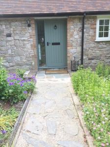 a stone house with a blue door and some flowers at Station Lodge South in Nannerch