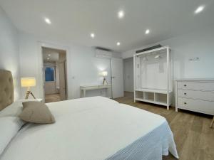 a white bedroom with a large white bed and a dresser at VUT Correhuela in Salamanca
