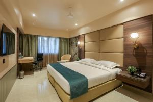 a hotel room with a large bed and a desk at Hotel Corporate in Navi Mumbai