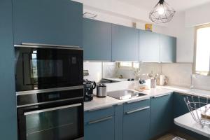 a kitchen with blue cabinets and a black refrigerator at Charming T2 "Sainte Marguerite" with air conditioning sea view and parking in Antibes