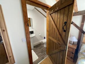 a bathroom with a wooden door and a toilet at The Cow Shed 2-Bed Apartment in Bradwell on Sea in Bradwell on Sea