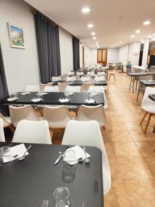uma grande sala com mesas e cadeiras brancas em Hotel Acebo Plaza Mayor em Jaca