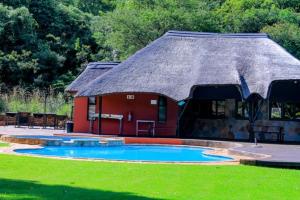 a small red building with a pool in a yard at Mount Azimbo Lodge in Louis Trichardt