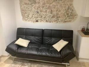 a black leather couch in a living room with two pillows at Charmant deux pièces dans le vieil Antibes Safranier in Antibes