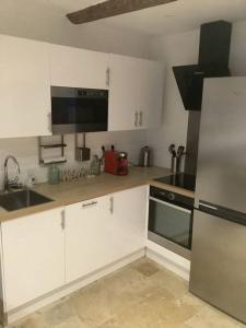 a kitchen with white cabinets and a sink and a refrigerator at Charmant deux pièces dans le vieil Antibes Safranier in Antibes