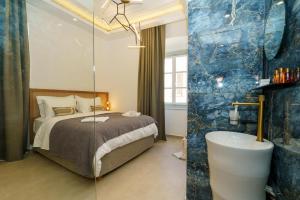 La Vie Hydra Luxury Suites في هيدرا: غرفة نوم مع سرير وحوض استحمام في غرفة