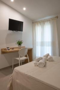 a bedroom with a bed with a desk and a television at Tarsis Guest House in Baunei