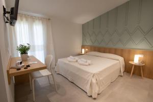 a bedroom with a bed and a table and a desk at Tarsis Guest House in Baunei