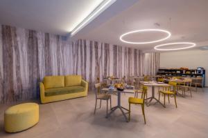 a restaurant with tables and chairs and a yellow couch at Tarsis Guest House in Baunei