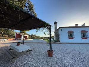 uma mesa e um banco em frente a uma casa em CORTIJO RURAL FLOR DE CAZALLA em Cazalla de la Sierra