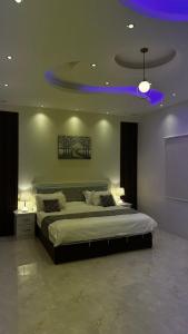 a bedroom with a large bed with a blue light at شاليهات و فلل عائلية بمسابح خاصة in Khamis Mushayt