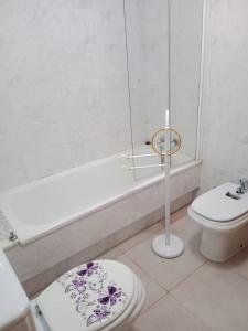 a white bathroom with a toilet and a bath tub at Apartamento Oceano in Barreiros