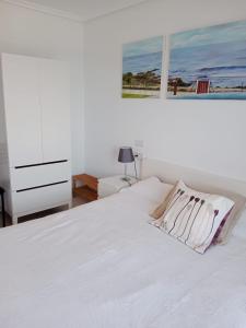 a white bedroom with a white bed and a dresser at Apartamento Oceano in Barreiros