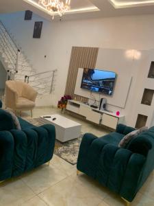 sala de estar con 2 sofás azules y TV en Jilles apartments -4bedroomduplex24hrlight&security en Lekki