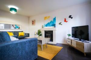 sala de estar con sofá azul y TV en Entire 4BR House in Luton - Near M1 & Airport, FREE Parking, en Luton