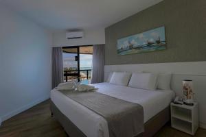 a bedroom with a large white bed and a window at Maceió Atlantic Suites in Maceió