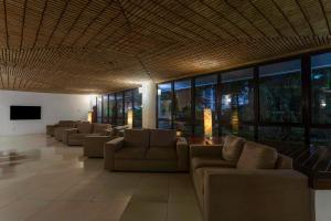 a living room with couches and a tv and windows at Maceió Atlantic Suites in Maceió