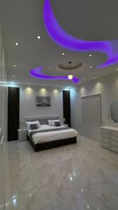 a bedroom with a large bed with a purple ceiling at شاليهات و فلل عائلية بمسابح خاصة in Khamis Mushayt