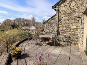 a patio with a table and chairs and a stone building at Oak Bank in Windermere