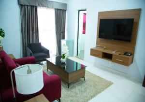 a living room with a television and red chairs at ONYX HOTEL Yamoussoukro in Yamussukro
