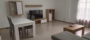 uma sala de estar com uma mesa e uma televisão em Maravilloso piso de dos dormitorios en Huéscar em Huéscar