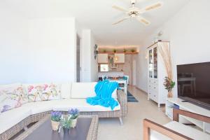 a living room with a white couch and a tv at Bungalow Playa dOr 4 in Cala d´Or
