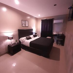 Schlafzimmer mit einem schwarzen Bett und einem Tisch in der Unterkunft Hotel La Terminal in San Miguel de Tucumán