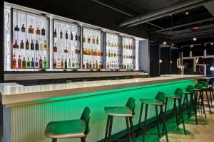 een bar met groene krukken en flessen alcohol bij Aloft Secaucus Meadowlands in Secaucus