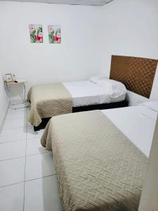 2 camas en una habitación de hotel con paredes blancas en Residencial Lassonde Guest House en David