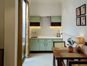 eine Küche mit grünen Schränken und einem Holztisch in der Unterkunft Cape House in Amritsar